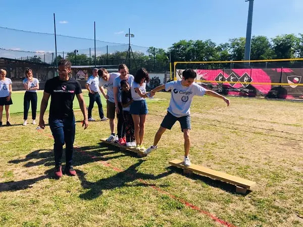 Participants réalisant un défi d’équilibre et de coopération sur des planches en bois en plein air